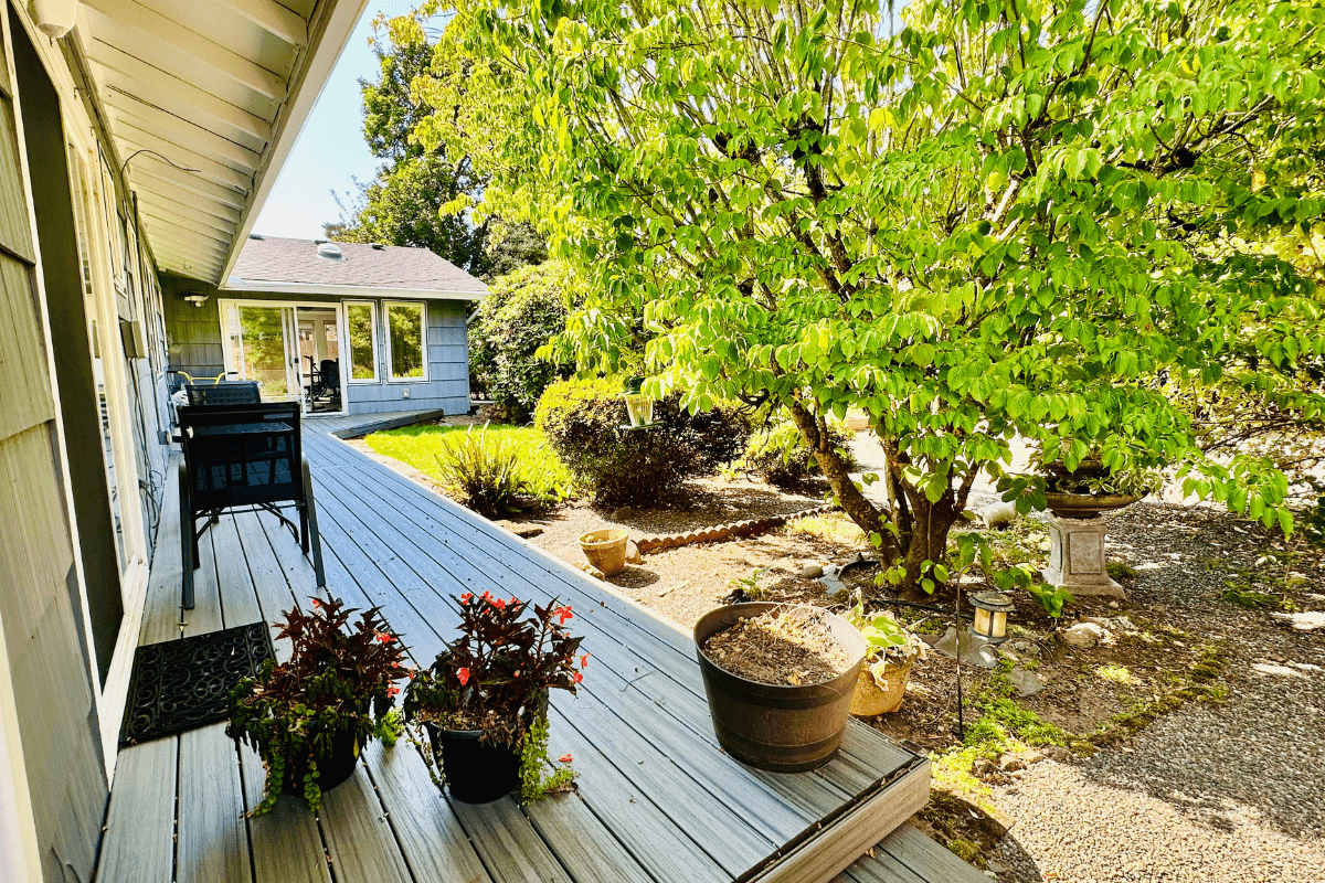 Inviting outdoor deck with seating and potted plants, overlooking a peaceful garden space for relaxation.